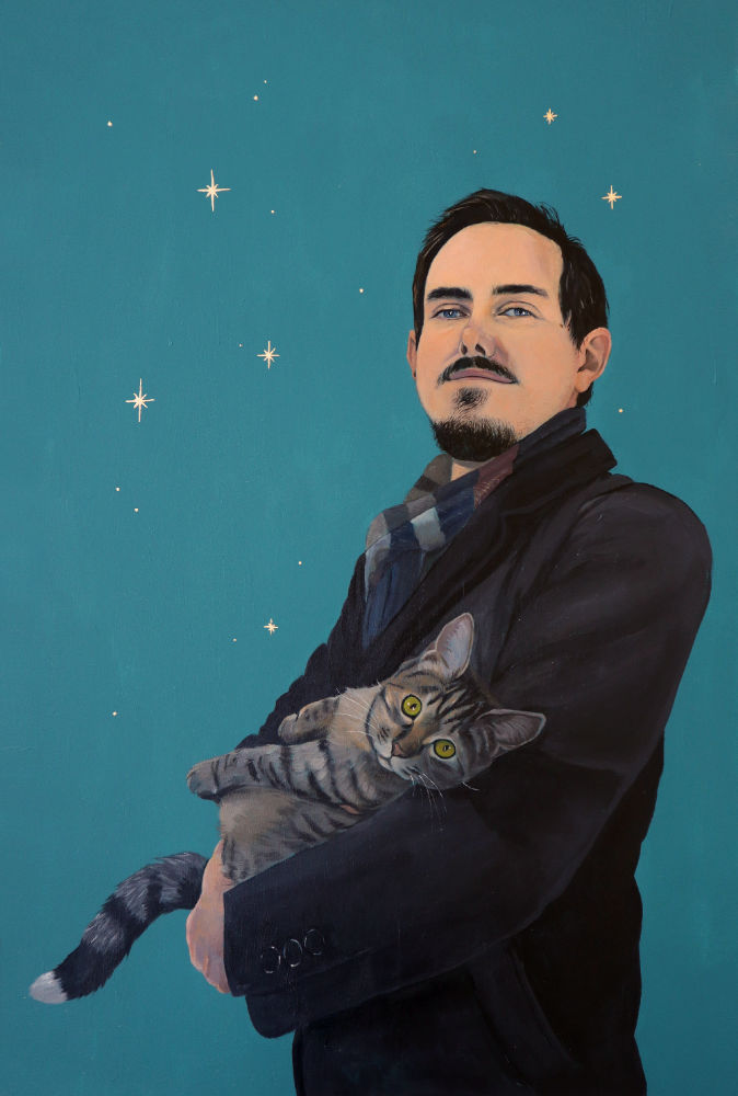 Painting of Nathan in a large grey coat, looking at the viewer and holding a tabby kitten. The background is turquoise with gold leaf stars.