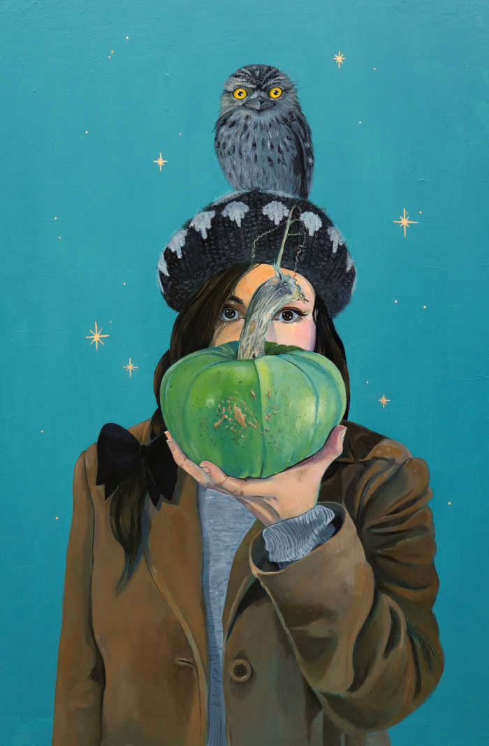 Painting of a self portrait of Lilly holding a green pumpkin in front of her face. She has a wooly brown and white cap on and a tawny frogmouth sitting on her head. The background is turquoise with gold leaf stars.